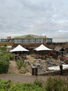 un restaurante con mesas y sombrillas frente a un edificio en Dawlish Warren Apartments, en Dawlish