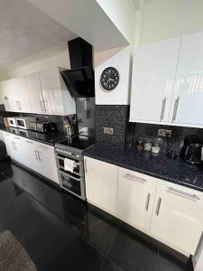 a kitchen with white cabinets and a clock on the wall at Winter Gardens large modern home in Blackpool