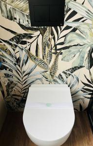 a white toilet in a bathroom with a plant wallpaper at AL CASCINALE PESCHIERA DEL GARDA in Peschiera del Garda