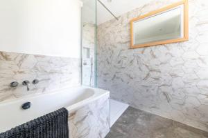 a bathroom with a white tub and a mirror at Eden Cottage in Whitstable