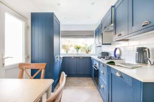 a kitchen with blue cabinets and a wooden table at Eden Cottage in Whitstable