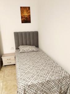 a bed with a gray headboard in a bedroom at DH Studio- City Center Tataouine in Tataouine