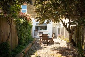 a garden with a table and chairs and a fence at Eden Cottage in Whitstable