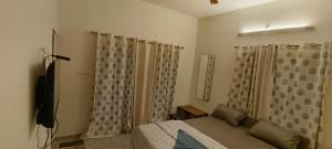 Schlafzimmer mit einem Bett und Vorhängen sowie einem TV in der Unterkunft PRS CREEK SIDE HOME STAY VILLA in Yelagiri