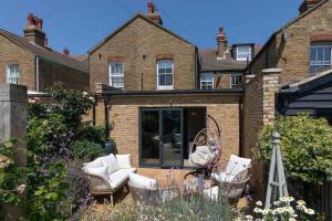 a garden with white furniture in front of a house at Goldfinch Cottage in Whitstable