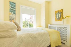 a bedroom with a white bed and a window at Goldfinch Cottage in Whitstable