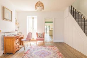 a living room with a staircase and a chair and a desk at Goldfinch Cottage in Whitstable