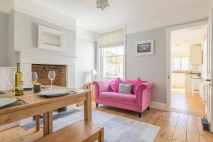 Jubilee Cottage في وايتستابل: غرفة معيشة مع أريكة وردية وطاولة