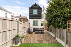 a backyard with a wooden fence and a table at Jubilee Cottage in Whitstable