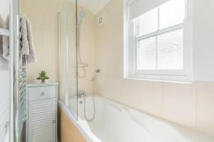 a white bathroom with a tub and a window at Jubilee Cottage in Whitstable +28 photos