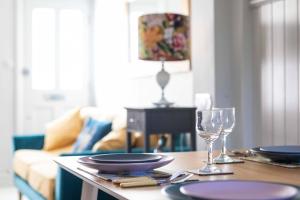a table with plates and wine glasses on top of it at Fig Tree Cottage in Whitstable