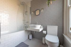 a white bathroom with a sink and a toilet at Fig Tree Cottage in Whitstable