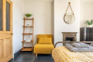 a bedroom with a bed and a chair and a mirror at Fig Tree Cottage in Whitstable