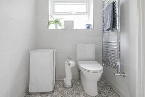 a white bathroom with a toilet and a window at Furlong Place in Whitstable