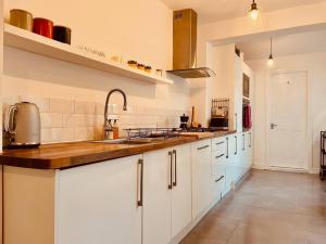 a kitchen with white cabinets and a wooden counter top at Seal Cottage in Whitstable