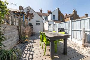 einen Holztisch und Stühle auf einer Terrasse mit einem Zaun in der Unterkunft Shell Cottage in Whitstable