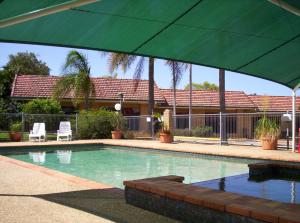 a person standing in front of a pool with an umbrella at Aspley Carsel Motor Inn in Brisbane