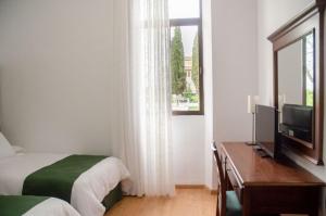 Habitación con 2 camas, TV y ventana. en Hotel Balneario de Marmolejo, en Marmolejo