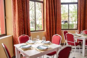 un comedor con mesas, sillas y ventanas en Hotel Balneario de Marmolejo, en Marmolejo