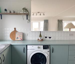 a kitchen with a washing machine and two glasses of wine at Peaceful Riverside Lodge in Christchurch