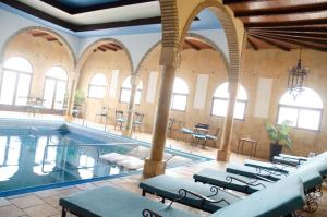a pool in a building with tables and chairs at Hotel Balneario de Marmolejo in Marmolejo