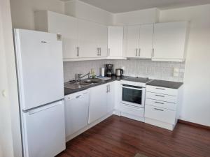 a white kitchen with white cabinets and a refrigerator at Apartment with fantastic seaview in Henningsvær. in Henningsvær