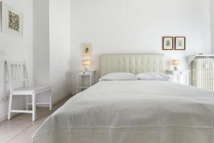 ein weißes Schlafzimmer mit einem weißen Bett und einem Stuhl in der Unterkunft Deluxe Home Verona in Verona