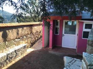 uma casa com uma porta rosa e uma parede de pedra em Suite Campestre Real del Monte em Mineral del Monte