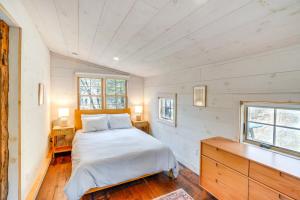 ein Schlafzimmer mit einem Bett, einer Kommode und zwei Fenstern in der Unterkunft Catskills Cabin on Wooded 100 Acres with Lake in West Coxsackie