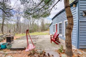 uma casa azul com uma cadeira vermelha ao lado de uma árvore em Catskills Cabin on Wooded 100 Acres with Lake em West Coxsackie
