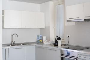una cocina blanca con armarios blancos y fregadero en B&B WelcHome, en Porto SantʼElpidio