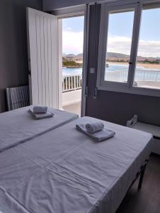 two beds in a bedroom with two large windows at Hotel Benimar in Isla