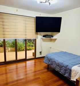 a bedroom with a bed and a flat screen tv at Descanso Urbano in Santiago
