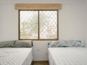 twee bedden in een kamer met een raam bij Suite departamento al pie de la playas con Aire acondicionado in Playas