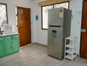 a kitchen with a refrigerator and green cabinets at Suite departamento al pie de la playas con Aire acondicionado in Playas