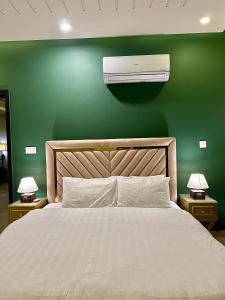 a bedroom with a bed and a air conditioner on a green wall at Serenity Corner 4 BHK in Islamabad