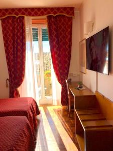a bedroom with a bed and a desk and a window at Hotel Arcadia in Macerata