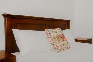 un letto bianco con testiera in legno e cuscino di Tekkawatta a Colombo