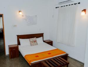 ein Schlafzimmer mit einem Bett mit weißer Bettwäsche und einer orangefarbenen Decke in der Unterkunft Tekkawatta in Colombo
