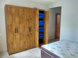 1 dormitorio con armario de madera y almohadas azules en Casa Temporada Monte H Piuma., en Piúma