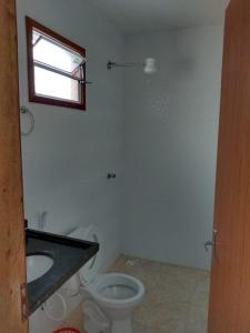 baño con aseo y lavabo y ventana en Casa Temporada Monte H Piuma., en Piúma