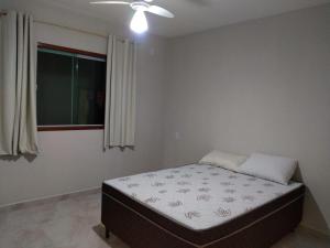 1 cama en un dormitorio con ventilador de techo en Casa Temporada Monte H Piuma. en Piúma