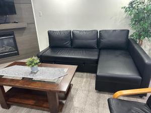 a black leather couch in a living room with a coffee table at Private Vacation Guest Suite Near Beach in White Rock