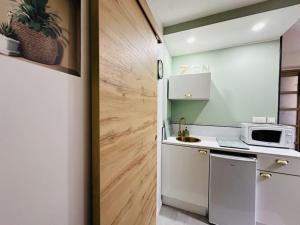 a small kitchen with white cabinets and a microwave at Studio Cosy in Saint-Gilles