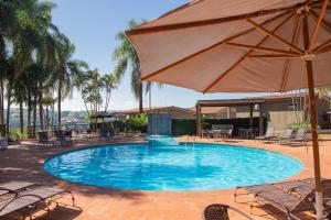 a large swimming pool with an umbrella and chairs at Panorama Park Hotel in Igarassú