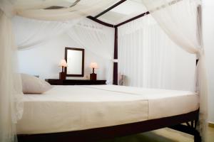 1 dormitorio con cama blanca y espejo en YKD Tourist Rest Hikkaduwa, en Hikkaduwa
