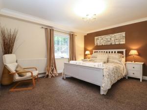 a bedroom with a bed and a chair and a window at 5 Ladstock Hall in Keswick