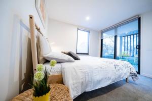 - une chambre avec un lit blanc et une grande fenêtre dans l'établissement Luxury and Stylish Apt on NB Ave, à Canberra