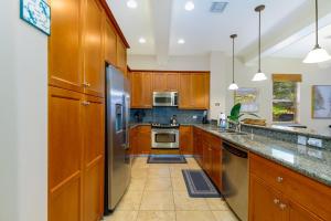 a kitchen with wooden cabinets and stainless steel appliances at Fairways at Mauna Lani #402 in Waikoloa