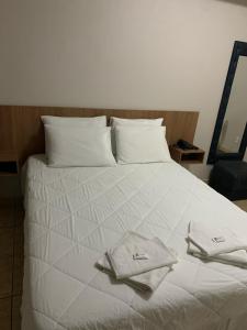 Una cama blanca con dos toallas encima. en Gran Lord Hotel en Pará de Minas